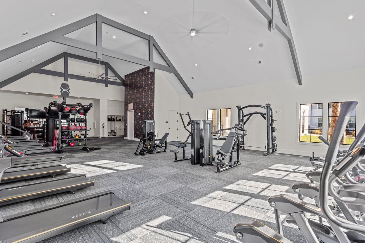 Bright fitness center with treadmills, weight machines, and free weights in a modern amenity space.