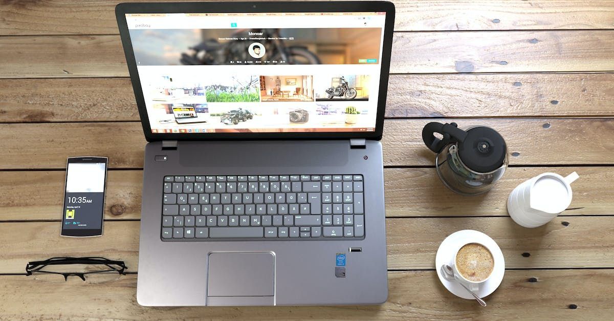 A laptop is open on a wooden table next to a cup of coffee.