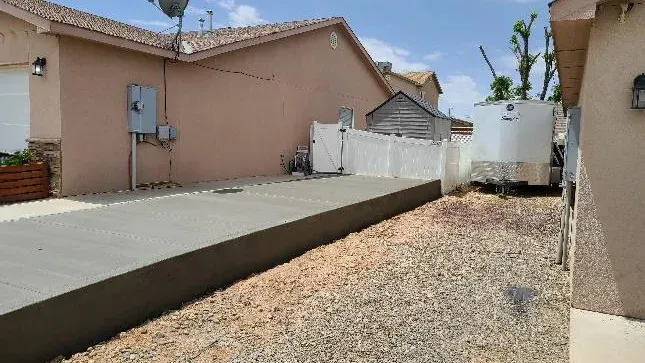 A concrete driveway is being built in the backyard of a house.