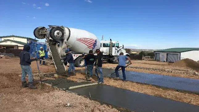 A group of construction workers are standing next to a concrete mixer truck.