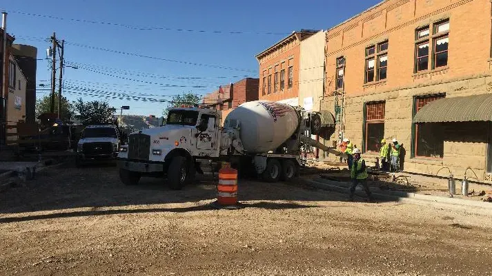 A concrete mixer truck is parked in front of a building.