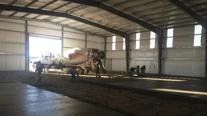 A concrete mixer truck is pouring concrete into a warehouse.