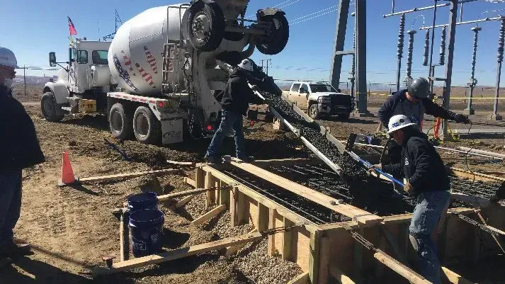 A concrete mixer truck is pouring concrete into a construction site.