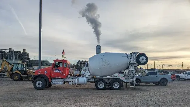 A concrete mixer truck is parked in a gravel lot.