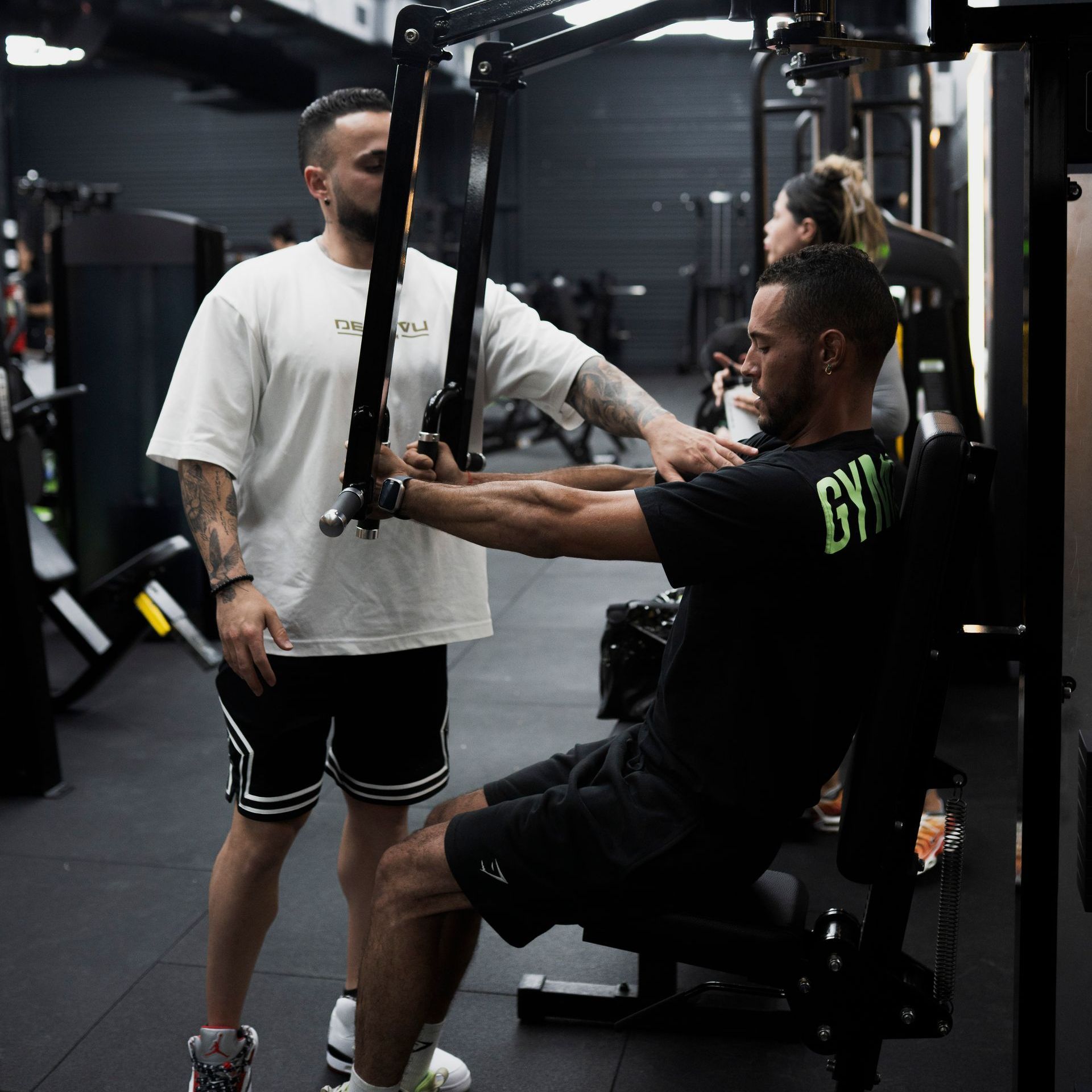 A man in a camo tank top is standing in a gym. DEJA VU GYM