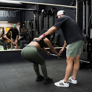 A man is helping a woman do leg presses in a gym. DEJA VU GYM