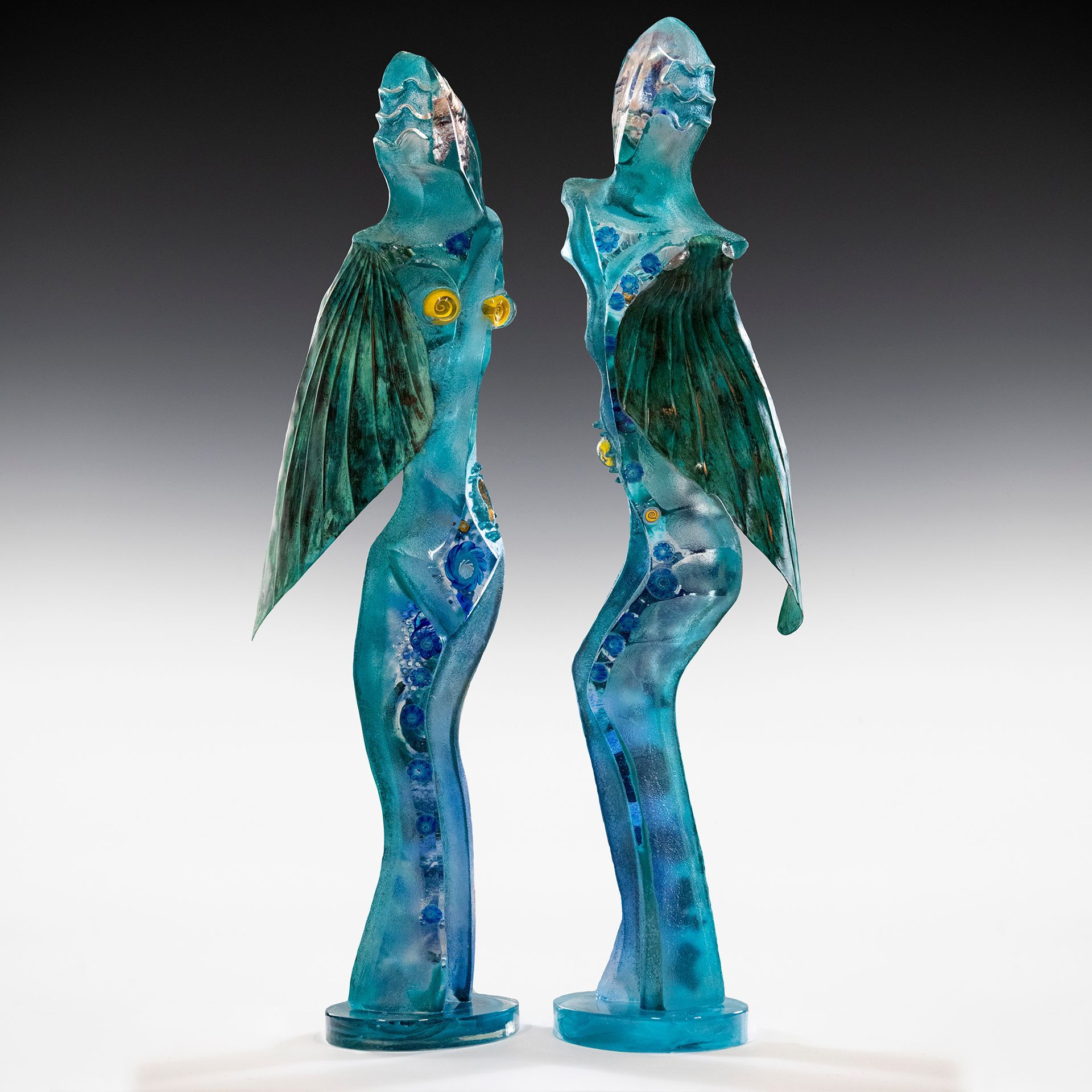 Two blue statues of a woman with wings are standing next to each other