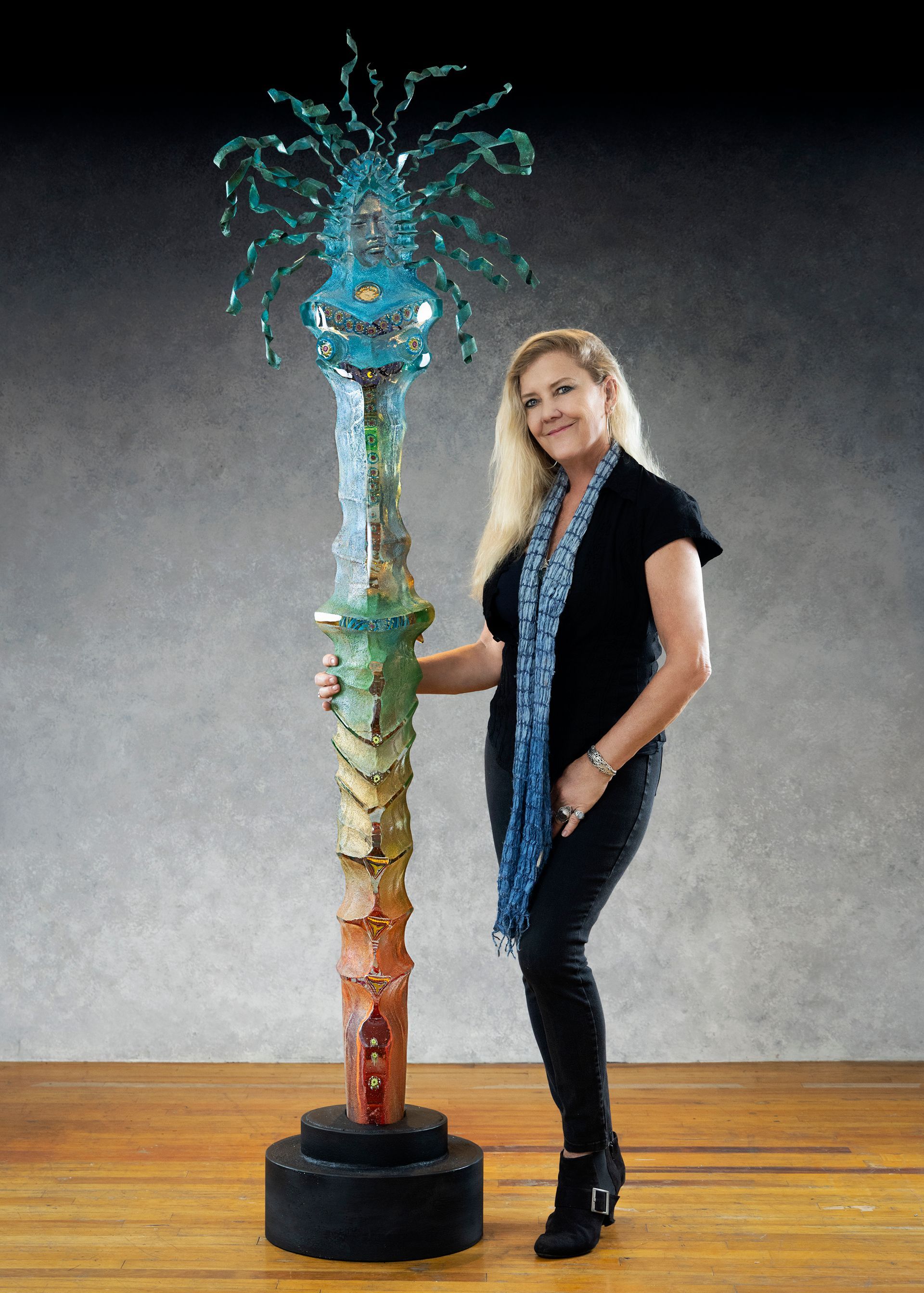 A woman is standing next to a tall sculpture