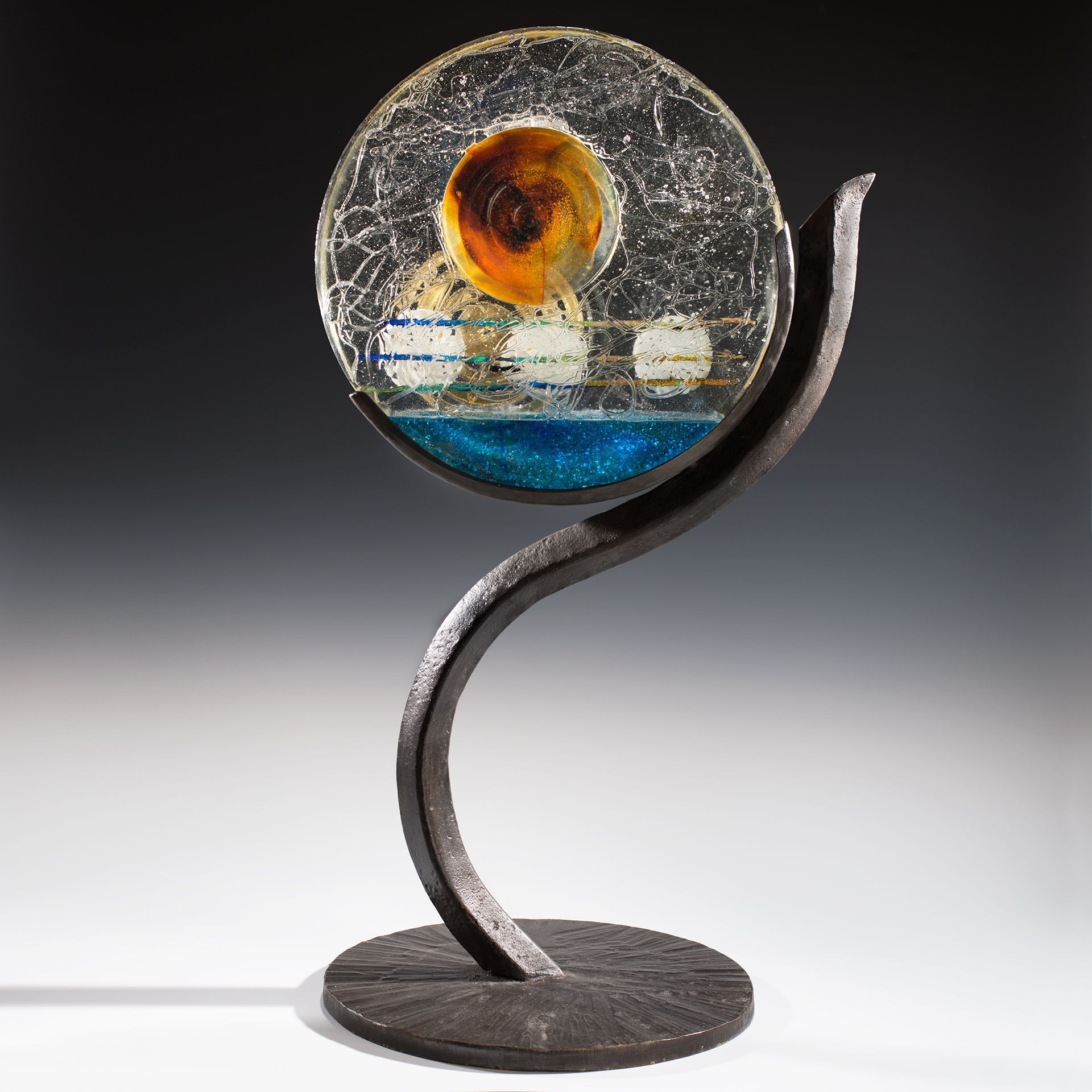 A glass sculpture is sitting on a metal stand