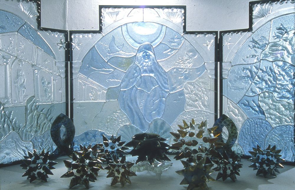 A stained glass window with a cross and flowers in front of it