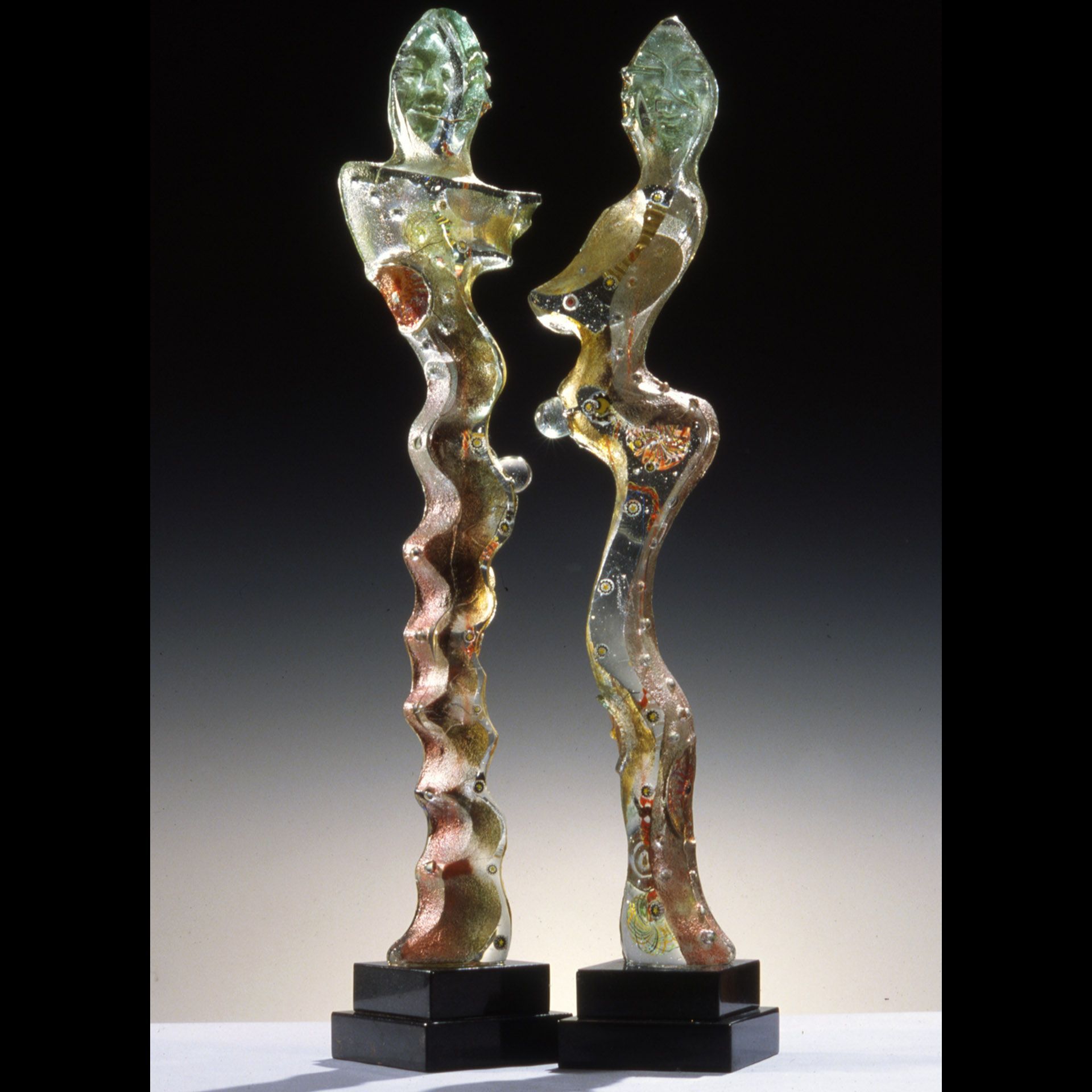 Two glass sculptures are standing next to each other on a table.