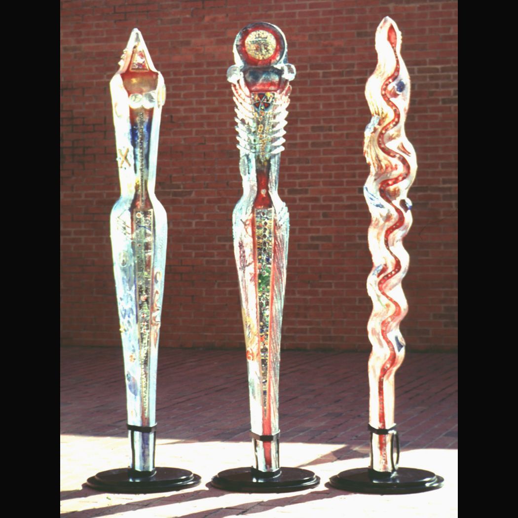 Three sculptures are lined up in front of a brick wall