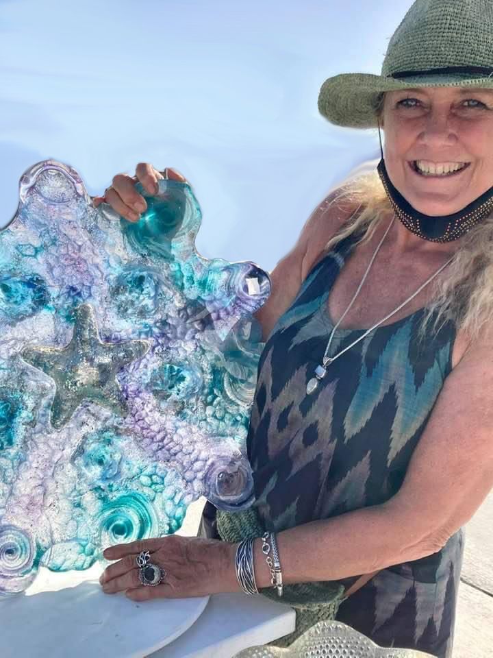 A woman in a hat is holding a piece of glass.