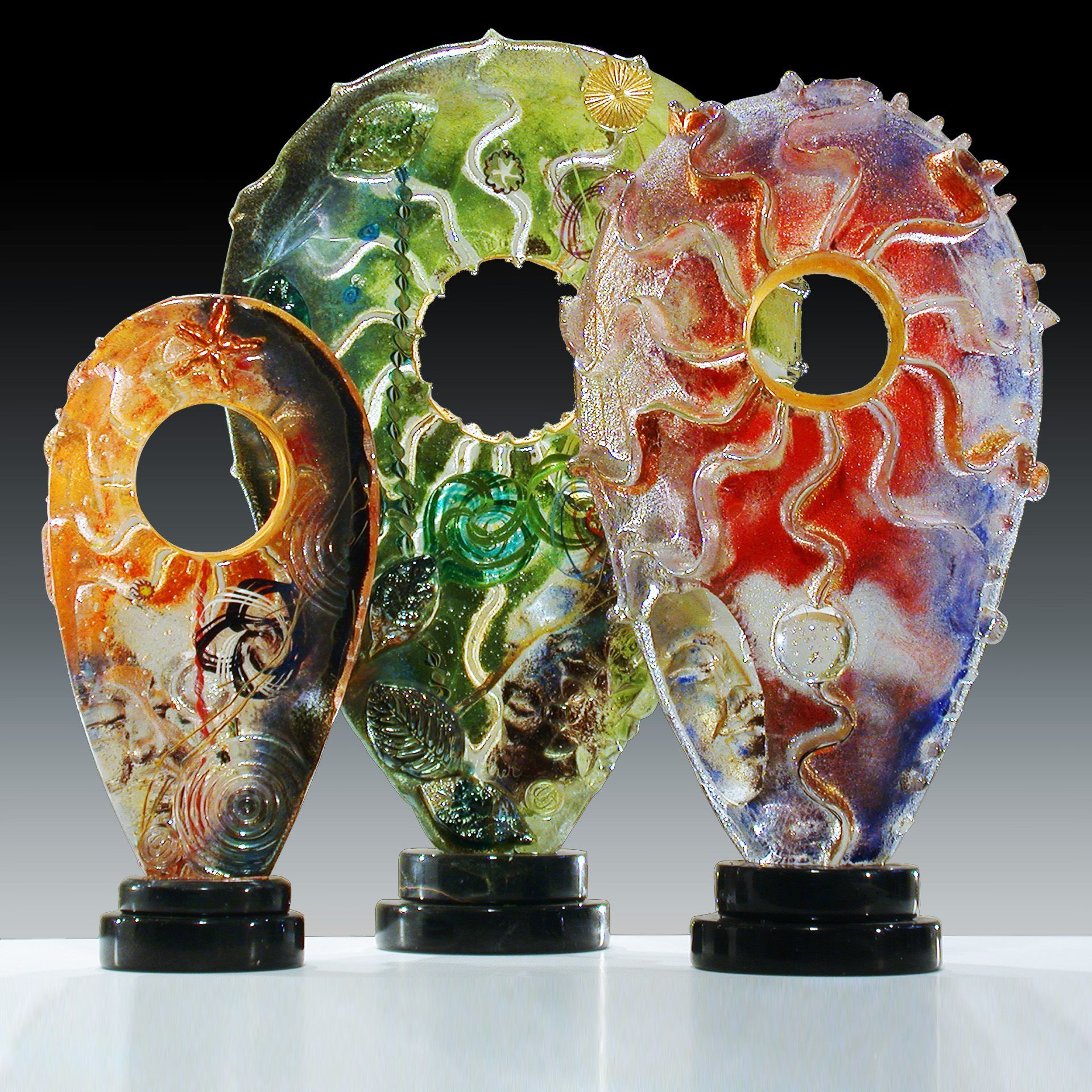 Three colorful glass sculptures are sitting on a table