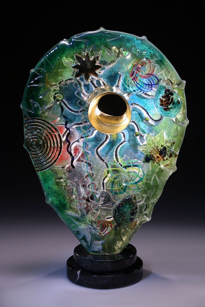 A green glass sculpture with a hole in the middle is sitting on a table.