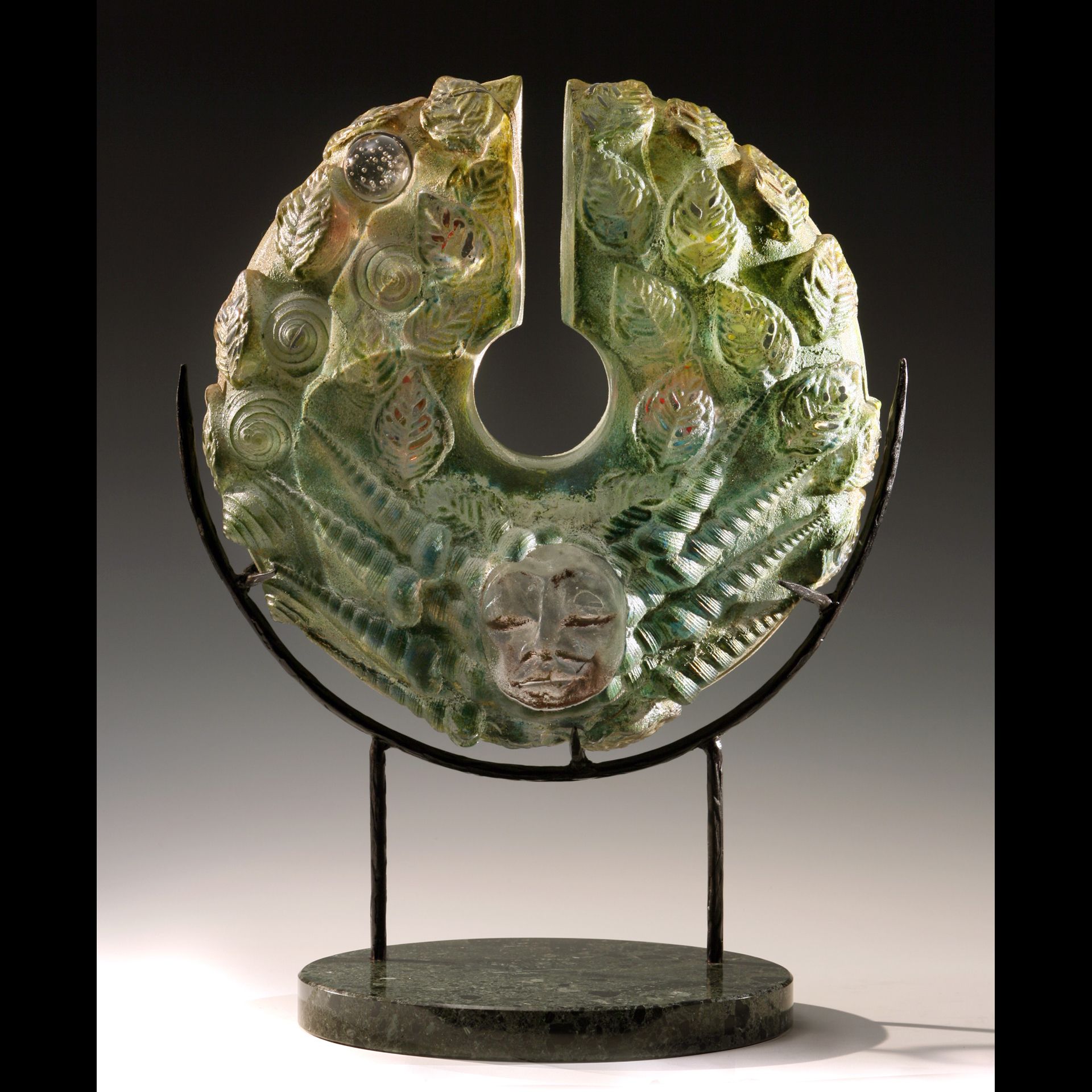 A green sculpture with a face carved into it