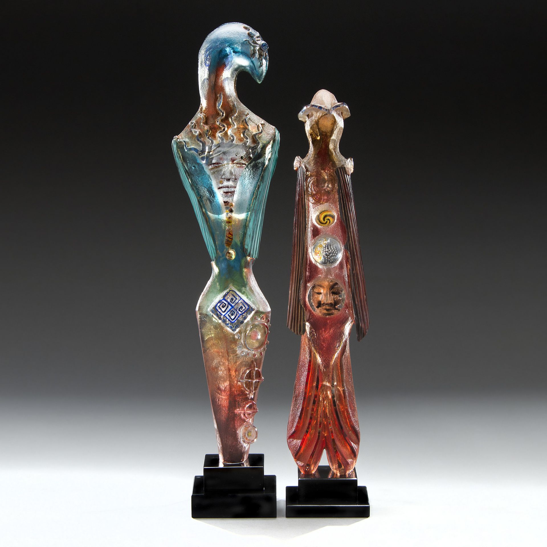 Two glass statues of a man and woman standing next to each other
