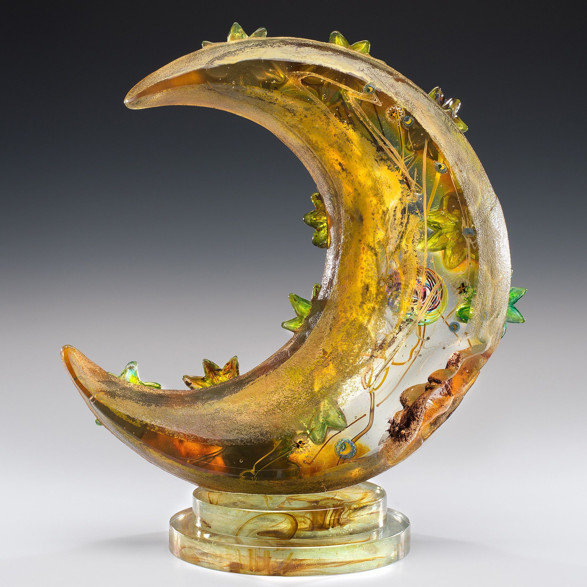 A glass sculpture of a crescent moon on a clear base
