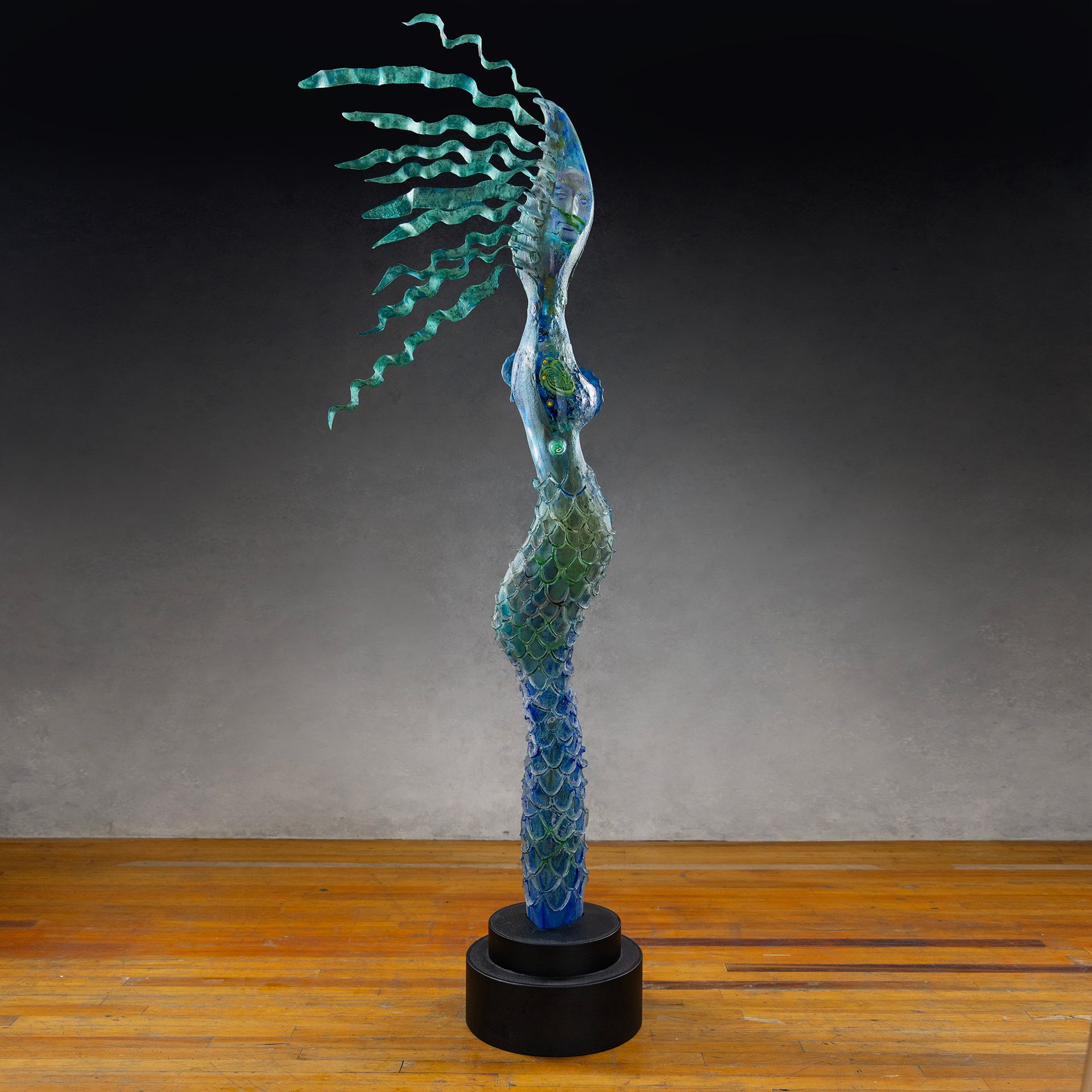 A statue of a woman with long hair is sitting on a wooden table