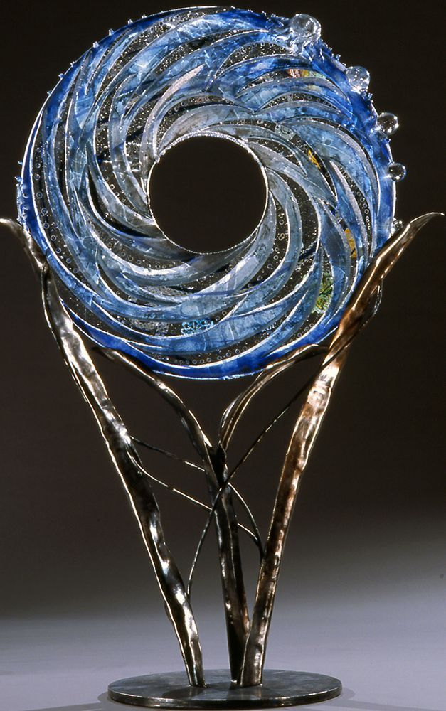 A blue glass sculpture is sitting on top of a metal stand.