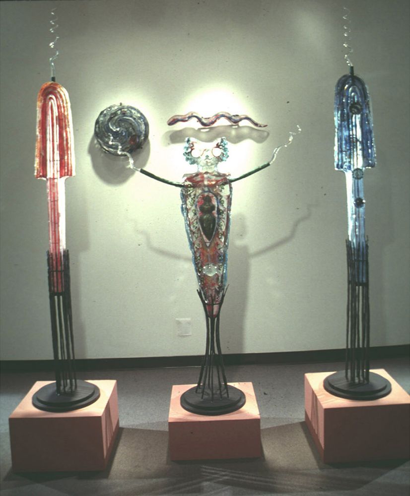 Three sculptures are on display in front of a wall