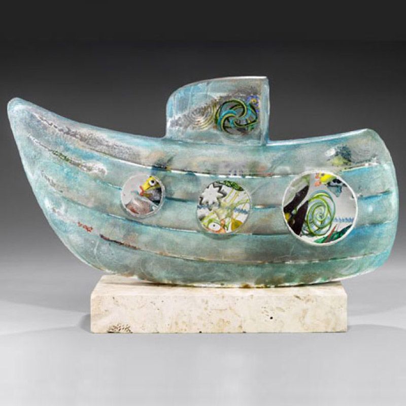 A glass sculpture of a boat is sitting on a marble base