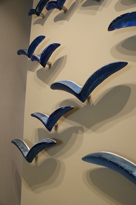 A row of blue birds are hanging on a wall
