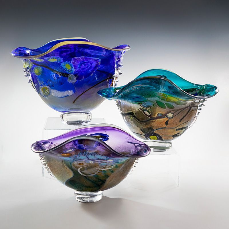 Three colorful glass bowls are sitting on top of each other on a table.