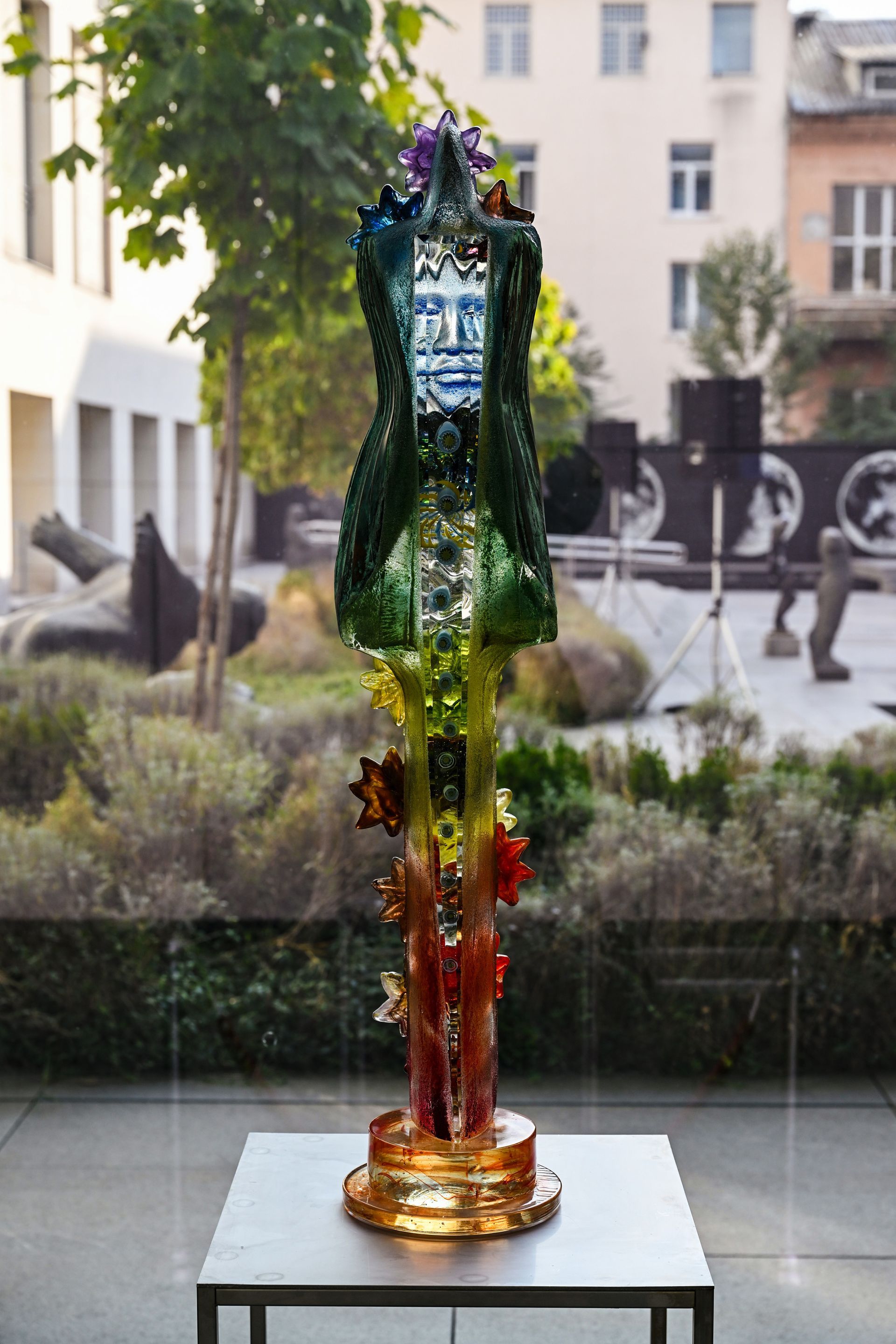 A statue of a woman is sitting on a table in front of a window.