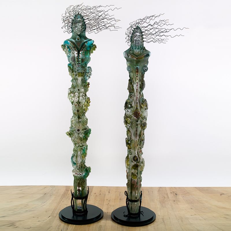 Two sculptures are sitting on a wooden table