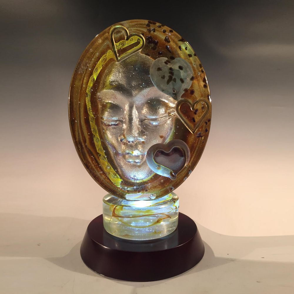 A glass sculpture of a woman 's face with hearts around it