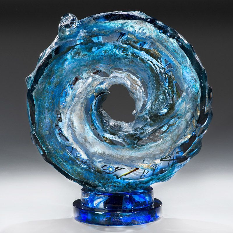 A blue glass sculpture of a wave on a blue base