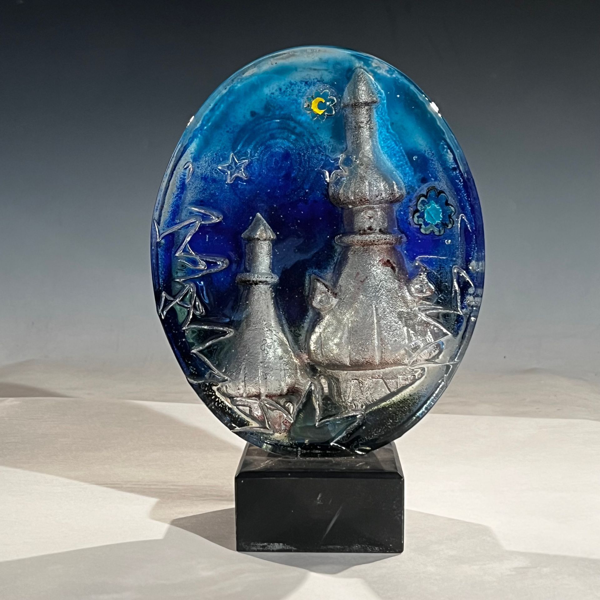 A blue glass sculpture with a castle on it