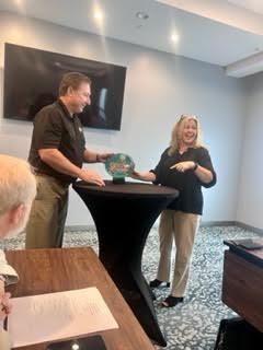 A man is giving a trophy to a woman in a room.