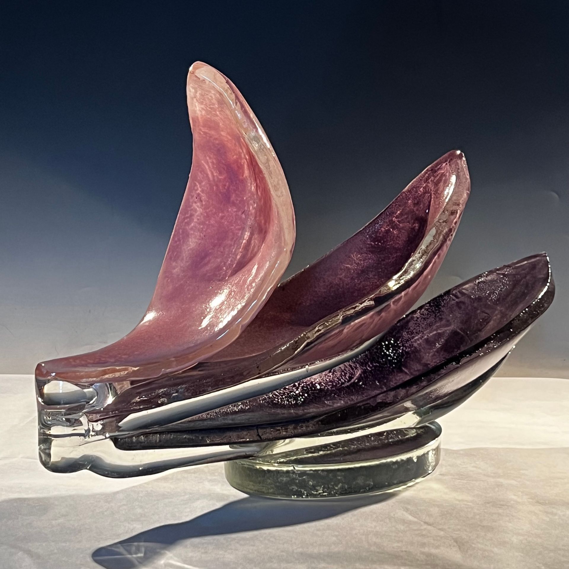 A purple glass sculpture is sitting on a glass base