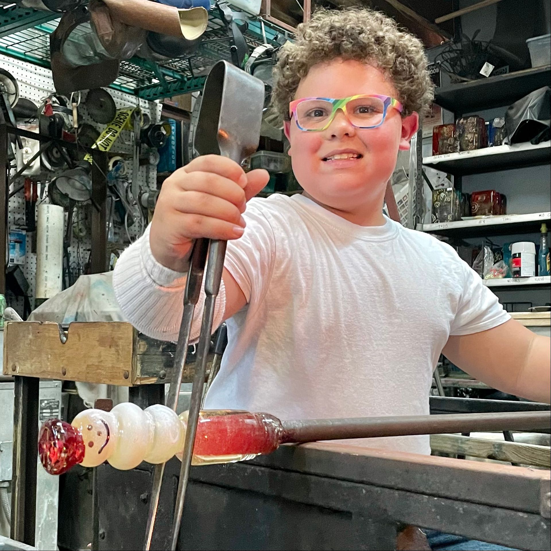 A young boy wearing glasses is holding a pair of tongs