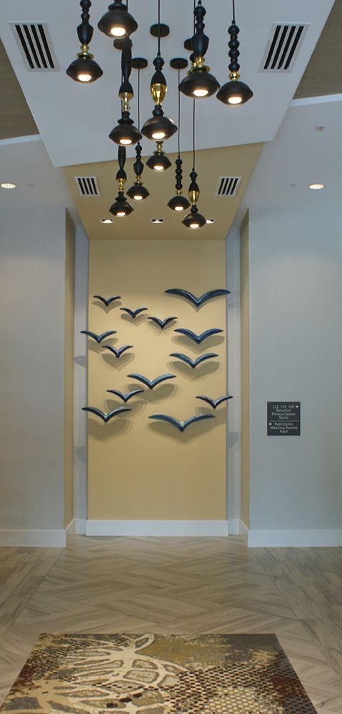 A hallway with birds on the wall and a chandelier hanging from the ceiling.