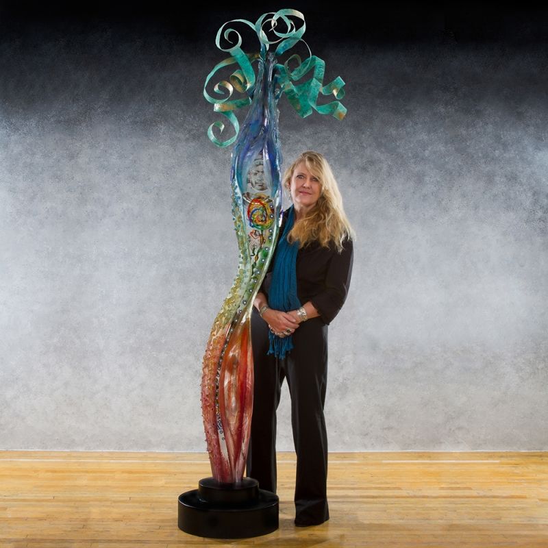 A woman is standing next to a sculpture on a wooden floor