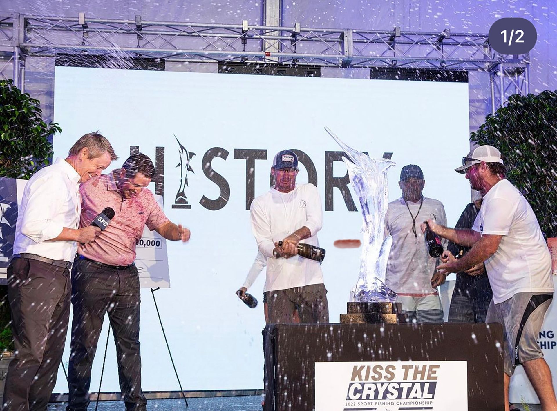 A group of men are standing in front of a sign that says kiss the crystal.