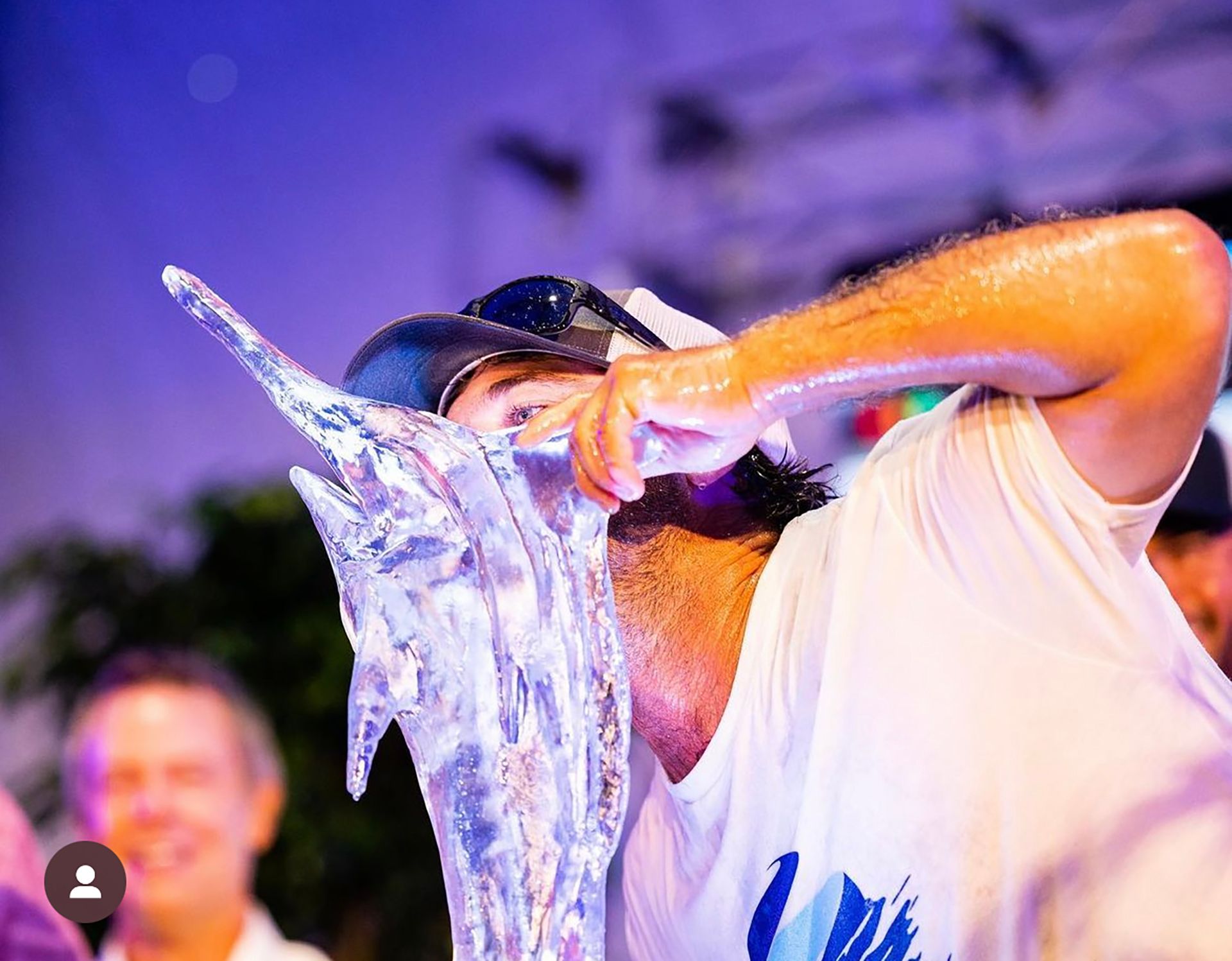 A man is drinking from a large ice sculpture.