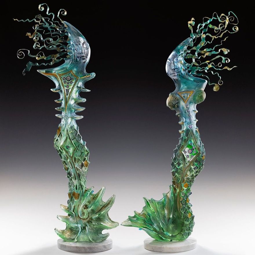 A pair of green and blue sculptures standing next to each other on a table.