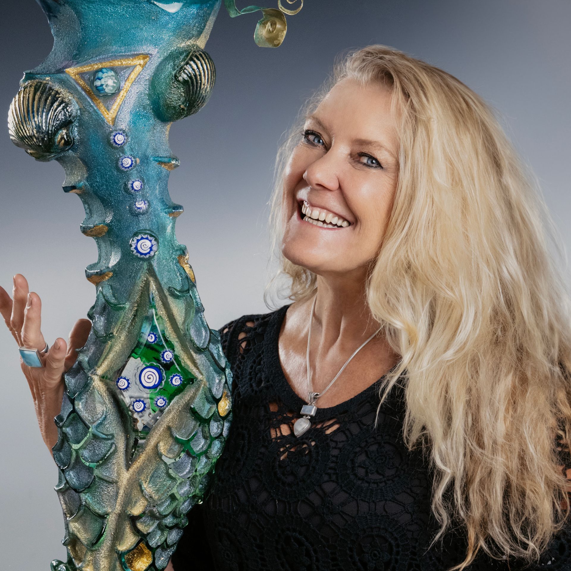 A woman is smiling while holding a large vase