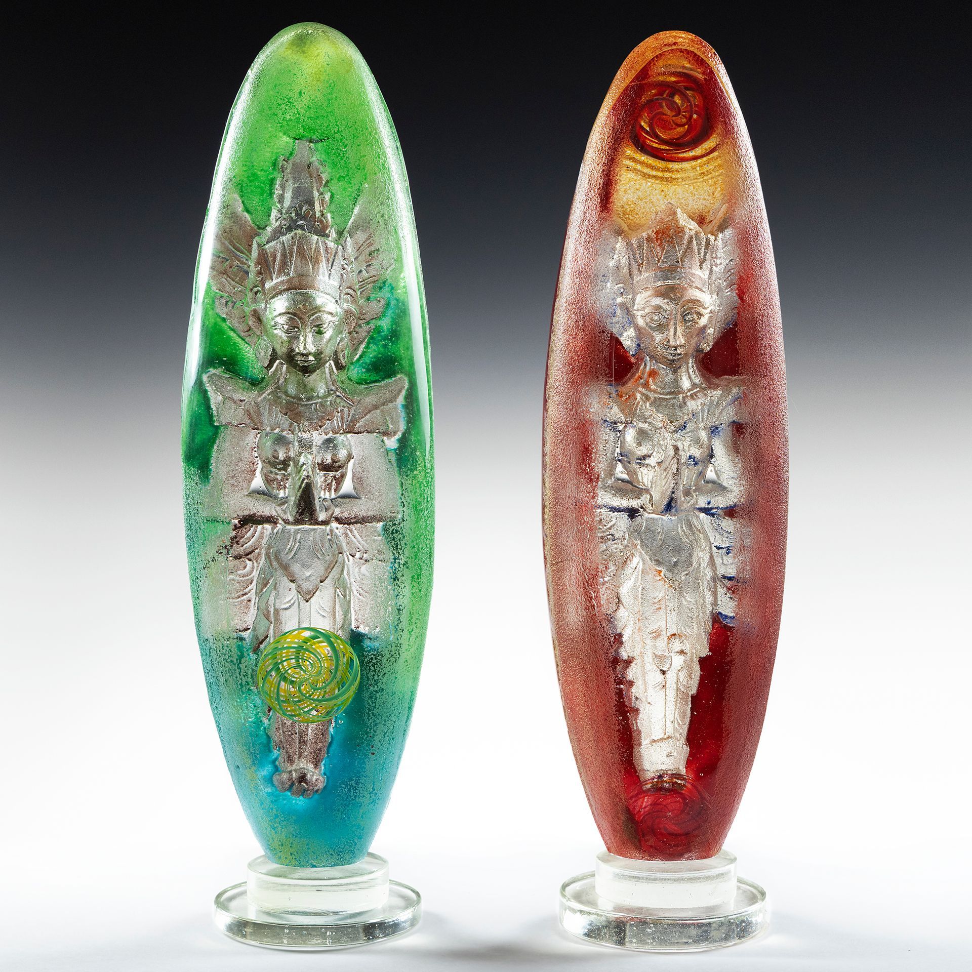 A green and a red glass object with a statue inside of them