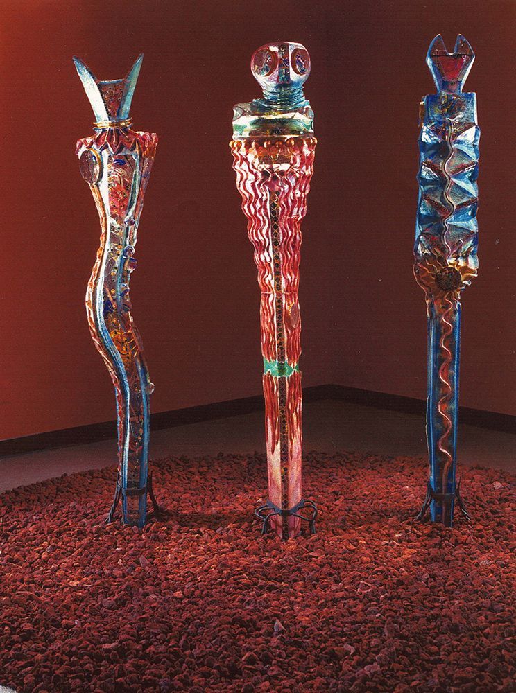 Three sculptures in a room with a red wall