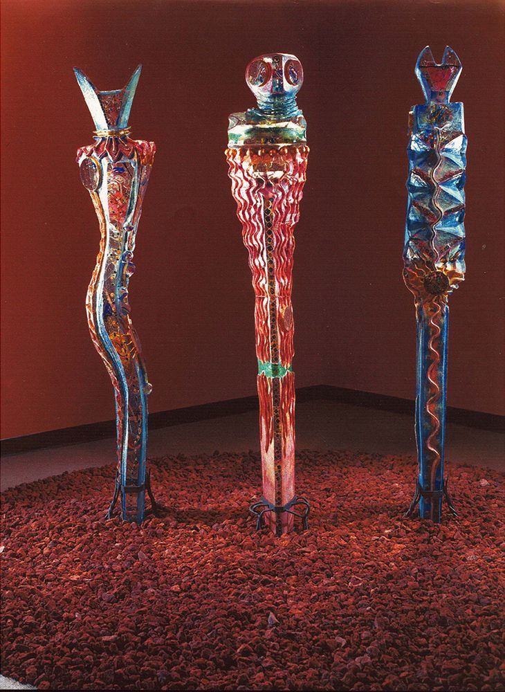 Three colorful sculptures in a room with a red wall