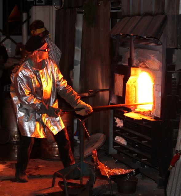 A man is standing in front of a glass furnace