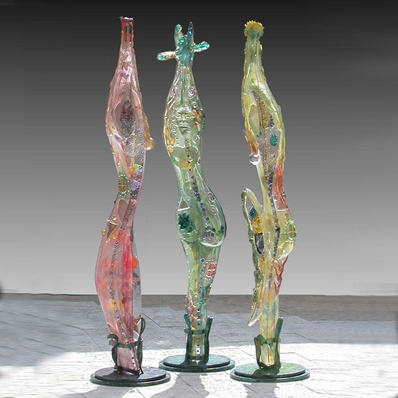 Three glass sculptures are sitting on a tiled floor
