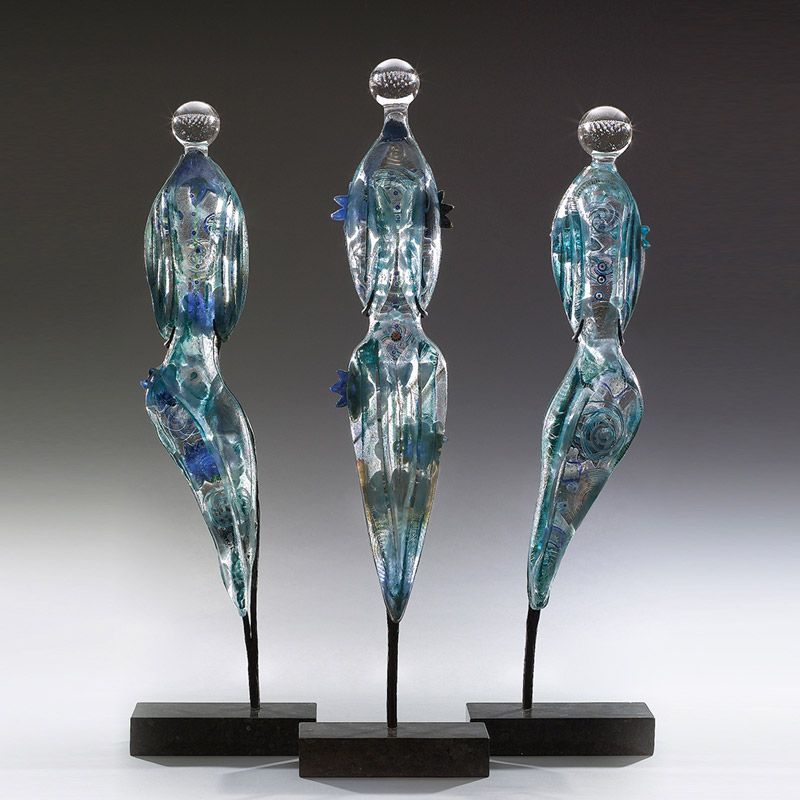 Three glass sculptures are sitting on wooden stands