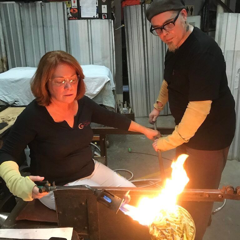 A man and a woman are working on a piece of glass