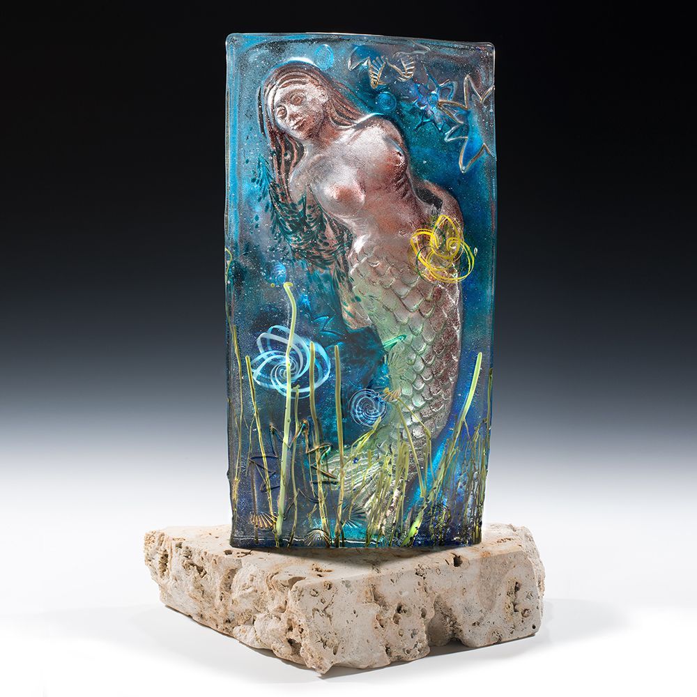 A statue of a mermaid is sitting on a rock